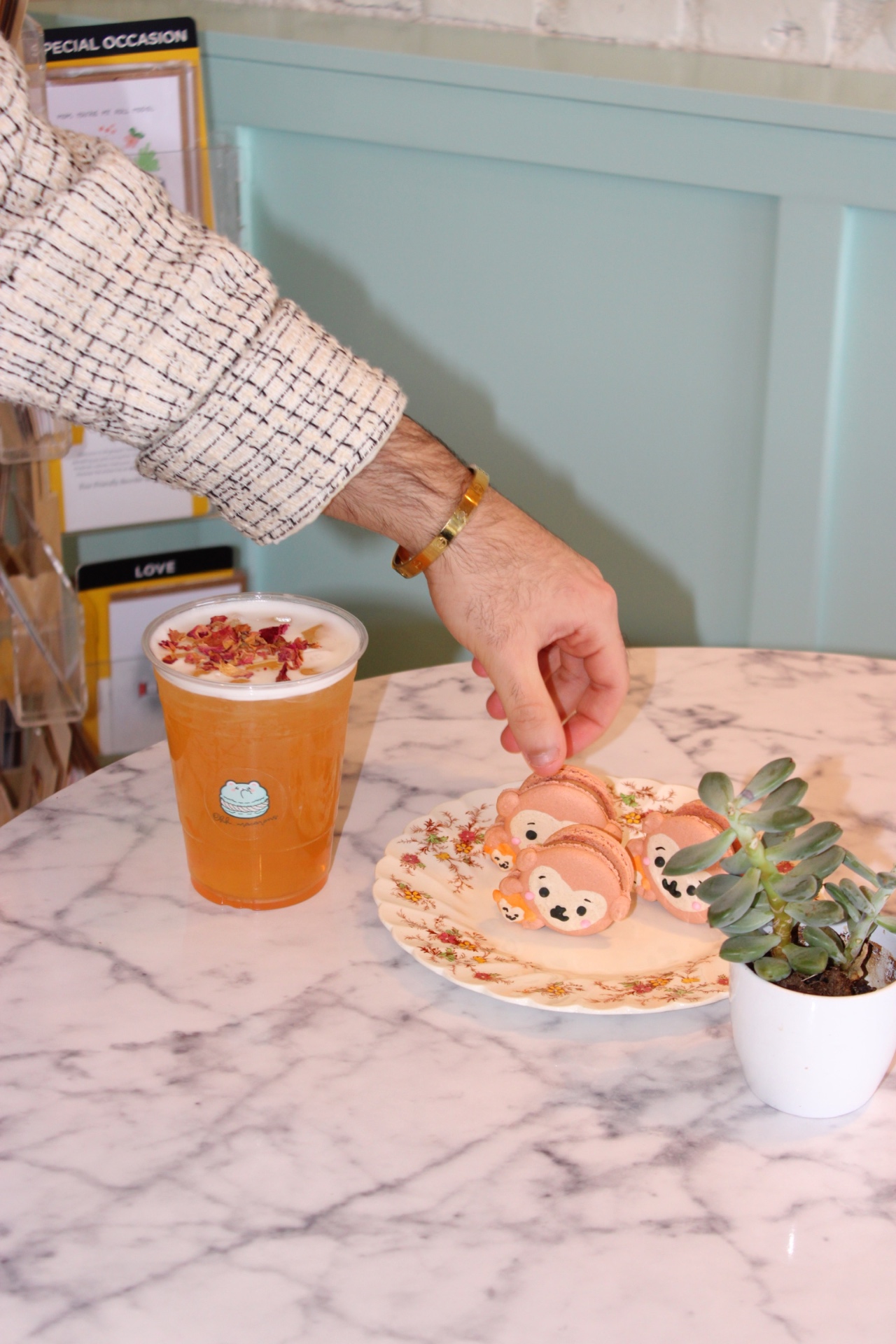 Rose-topped drink and monkey macarons on marble table