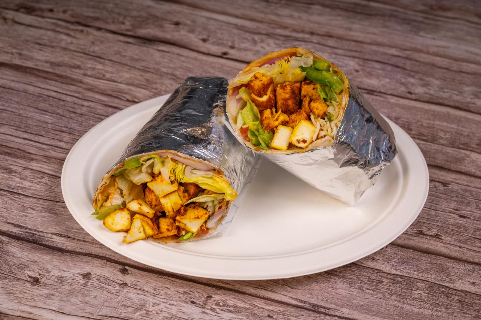 Paneer tikka wrap cut open on a white plate